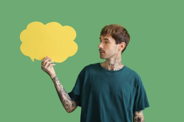 Yeşil arka planda boş konuşma balonu olan mutlu genç adam.