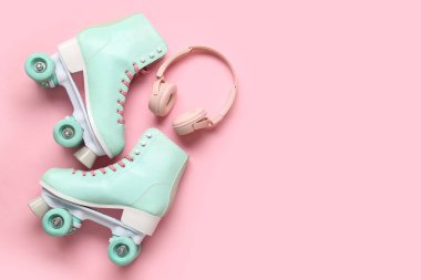 Pembe arka planda bir çift eski paten ve modern kulaklık.