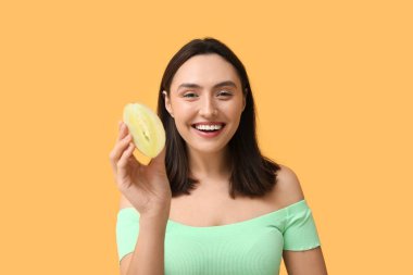 Beautiful young woman with chikoo fruit on yellow background clipart