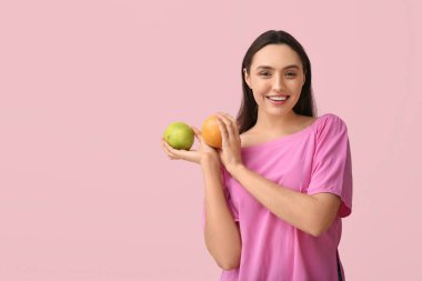 Pembe arka planda lezzetli greyfurtlu ve bergamotlu güzel genç bir kadın.