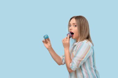 Mavi arka planda tatlı badem kurabiyeleri olan güzel genç bir kadın.