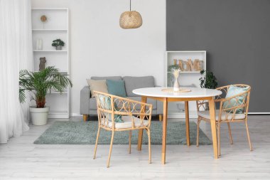 Masası, koltukları, rahat koltuğu, çiçekleri ve raf ünitesi olan modern oturma odasının güzel iç mekanı.