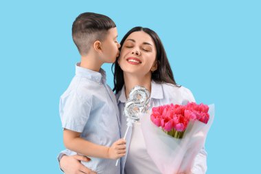 Sevimli küçük çocuk mavi arka planda Uluslararası Kadınlar Günü 'yle annesini selamlıyor.