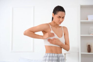 Yatak odasında göğüslerini kontrol eden güzel bir kadın. Kanser farkındalığı kavramı