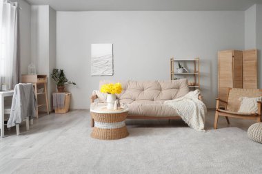 Şık bir oturma odası. Kanepesi, narsisli çiçekleri ve kahve masası var.