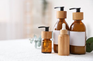 Kozmetik ürünler ve okaliptüs dalları banyodaki masada, yakın plan.