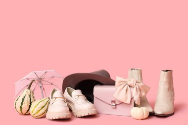 Kahverengi şapkalı farklı ayakkabılar, şık çanta, pembeli fiyonk, şemsiye ve balkabağı.