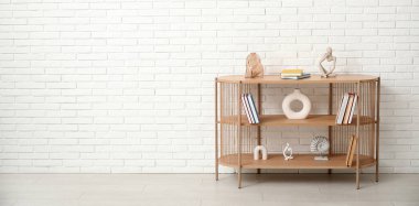 Kitapları ve dekorasyonları olan raf ünitesi beyaz tuğla duvarın yanında. Tasarım için pankart