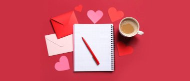 Kırmızı zemin üzerinde defter, kağıt kalpler ve bir fincan kahve olan zarflar. Sevgililer Günü kutlaması