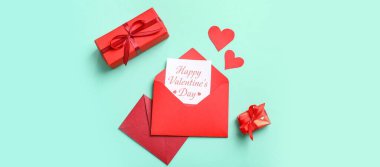 Kartlı zarflar, hediye kutuları ve turkuaz arka planda kağıt kalpler. Sevgililer Günü kutlaması