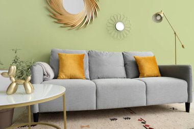 Oturma odasının iç tarafında yastıkları ve kahve masası olan rahat gri bir kanepe.