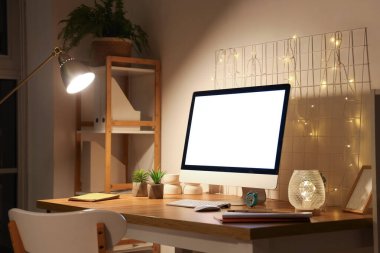 Boş bilgisayar monitörlü işyeri, geceleri ofiste parlayan ışıklar ve pano.