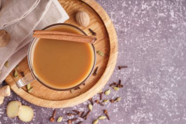 Arkaplanda farklı baharatlar olan bir bardak lezzetli masala çayı, yakın plan.