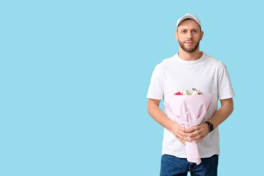 Mavi arka planda bir buket güzel lalesi olan genç teslimatçı.