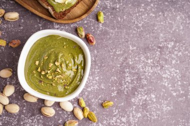 Gri grunge arka planda bir kase lezzetli fıstık ezmesi.