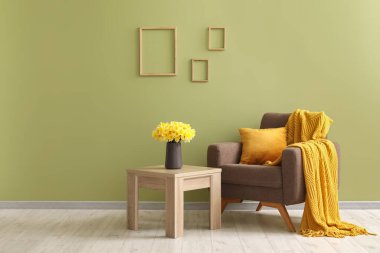 Kareli rahat bir koltuk ve oturma odasında nergis çiçekleri olan kahve masası.