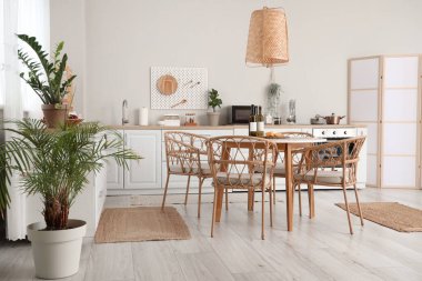 Beyaz tezgahları, yemek masası, sandalyeleri ve lambası olan güzel bir mutfak.