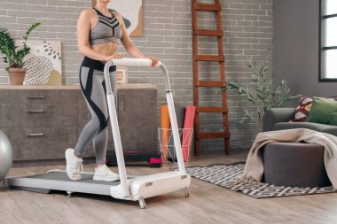 Spor kadın evde koşu bandında antrenman yapıyor.