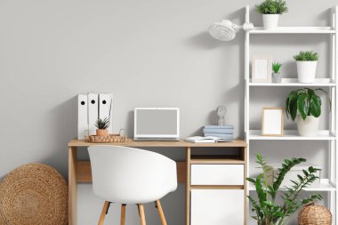 İşyerindeki dizüstü bilgisayarlı raflarda elektrikli vantilatör var.