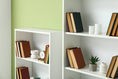 Odadaki yeşil duvarın yanındaki kitap rafları