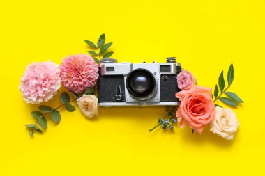 Klasik fotoğraf makineli kompozisyon ve sarı arka planda güzel çiçekler.