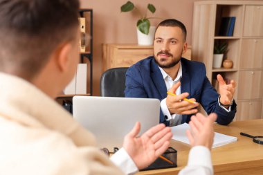 Erkek avukat, ofiste tekerlekli sandalyedeki adamla çalışıyor.