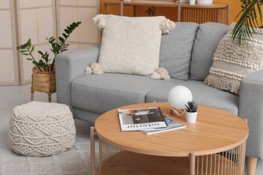 Modern oturma odasının içinde ahşap masalı gri kanepe.