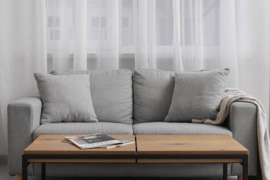 Modern oturma odasının içinde ahşap masalı gri kanepe.