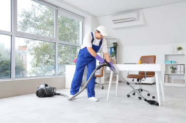 Temizlikçi ofiste yerleri süpürüyor.
