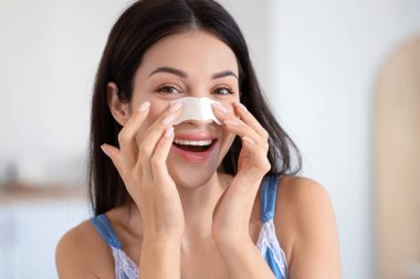 Evde burun bandı takan genç bir kadın.