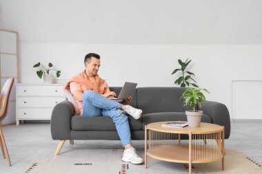 Adam kanepede otururken dizüstü bilgisayar ile