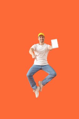 Turuncu arka planda tablet bilgisayarlı zıplayan adam. Tasarım için model