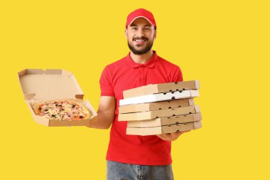 Sarı arka planda pizza kutuları olan erkek kurye.