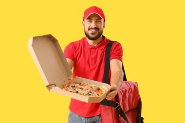 Sarı arka planda lezzetli pizzalı erkek kurye.