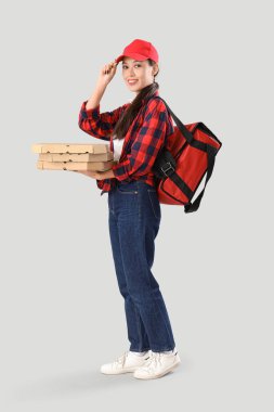 Gri arka planda pizza kutuları olan Asyalı kadın kurye.