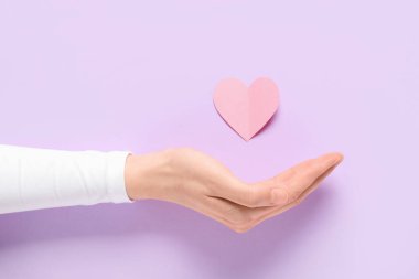 Leylak kaplamalı kağıt kalpli bir kadın, yakın plan. Sevgililer Günü kutlaması