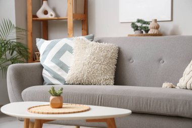 Oturma odasında yumuşak yastıklı gri kanepe.