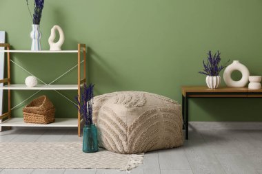 Oturma odasının içinde vazolarda raf ünitesi, puf ve lavanta çiçekleri var.