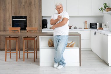 Şeker hastası, olgun bir adam mutfakta tükenmez kalem kullanıyor.