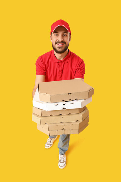 Male courier with pizza boxes on  yellow background