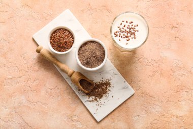 Keten tohumlu bir bardak taze yoğurt ve bej arka planda bir kase un.