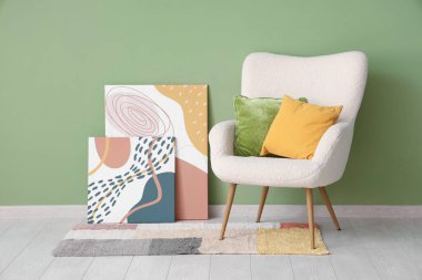 Yeşil duvarın yanında beyaz koltuklu, yastıklı ve resimli şık bir oturma odası.