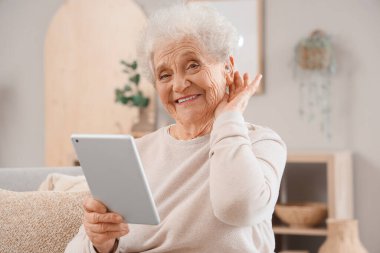 Evde tablet bilgisayar kullanan son sınıf öğrencisi bir kadın.