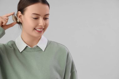 Arka planda işitme cihazı olan genç bir kadın, yakın plan.