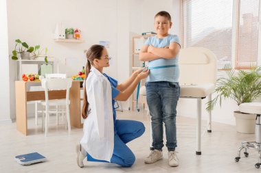 Kadın beslenme uzmanı, klinikte kilolu bir çocuğun karnını tartıyor. Diyet kavramı