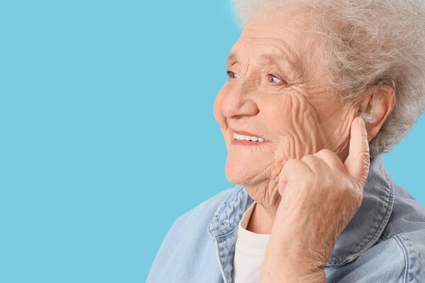 Старшая женщина со слуховым аппаратом на синем фоне, крупным планом