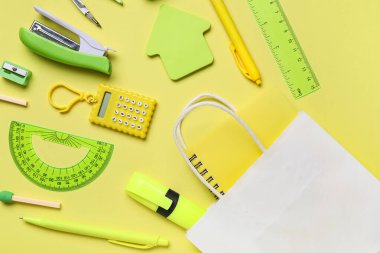 Sarı arka planda farklı okul kırtasiyesi olan alışveriş çantası.