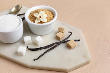 Aromatik vanilya şekeri, çiçek ve bej arkaplanlı çubuklar.