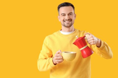 Yakışıklı adam gayzer kahve makinesinden fincana espresso dolduruyor.