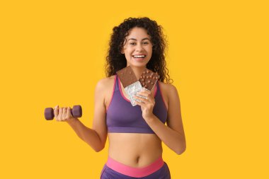 Güzel bir Afro-Amerikalı kadın. Çikolatalı ve sarı arka planda dambılı var.